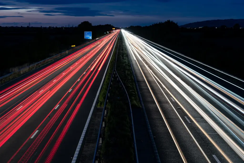 Nighttime highway scene near M5 Junction 9, Tewkesbury, with vehicle light trails and visible road signs for A46 and A438.